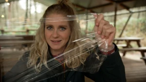 Een foto van Janouk die vershoudfolie straktrekt en er doorheen kijkt.