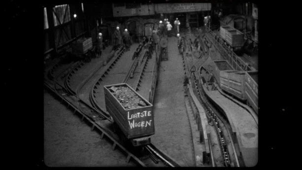 Een zwart-wit foto van een mijnkarretje met de tekst Laatste weken, het karretje staat op rails.