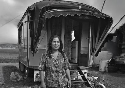 Zwartwitfoto van Romavrouw voor woonwagen.