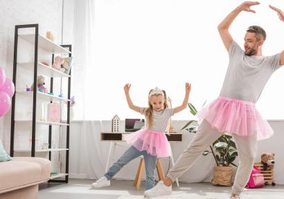 Foto van man met dochter in roze tutu aan het balletdansen in de woonkamer.