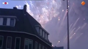 Een foto van een huis met op de achtergrond een grote rookwolkt en vuurwerk dat de lucht in gaat.