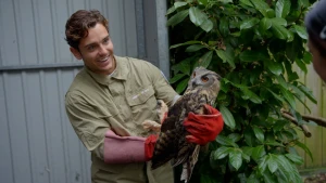Een foto van presentator Floris die een grote uil vasthoudt, hij heeft speciale beschermende handschoenen aan.
