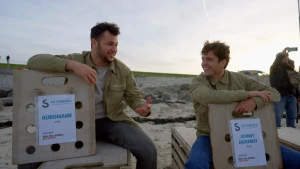 Floris en Haitam zitten op het strand op twee kisten waar zeehonden in zitten.