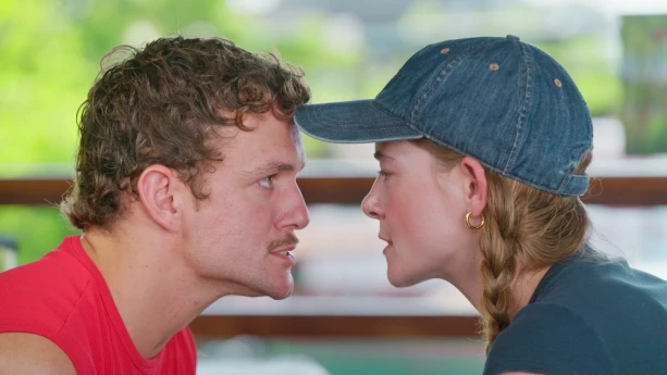 Een close-up foto van de beide presentatoren die elkaar aankijken, Jurre links en Emma rechts.