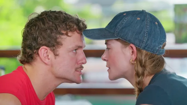 Een close-up foto van de beide presentatoren die elkaar aankijken, Jurre links en Emma rechts.