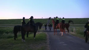 Veel politie te paard en lopend bij een dijk