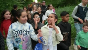 Een foto van kinderen die de avondvierdaagse wandelen. Vorop een meisje met een stitch shirt en een meisje met een geel jasje aan.