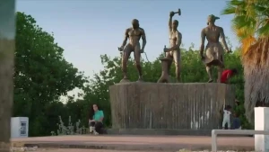 Een foto van de presentatrice die voor het Tulamonmument op Curacao zit.