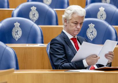 Foto van Geert Wilders die een document leest in de Tweede Kamer.