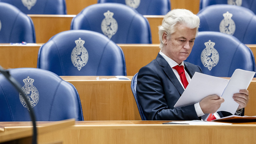 Foto van Geert Wilders die een document leest in de Tweede Kamer.