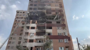 Een foto van een flatgebouw dta ernstige schade heeft door een bombardement, je ziet zwartgeblakerde stukken en het is kapot.