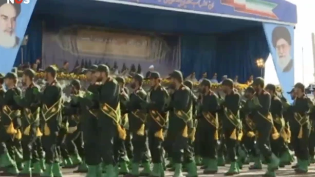 Foto van parade van soldaten die langs een podium lopen.