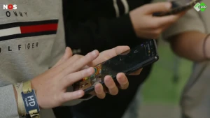 Een foto van een kinderhand die een mobiele telefoon vasthoudt.