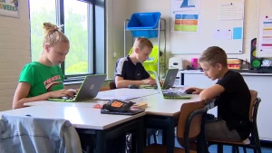 Een afbeelding van drie kinderen in de klas. Ze werken op hun laptop.
