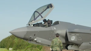 Militair vliegtuig met piloot in de cockpit en een militair op de grond