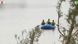 Een foto van reddingswerkers in een blauwe opblaas roeiboot.