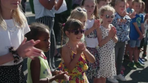 Kinderen in zomerse kleding klappen op het schoolplein