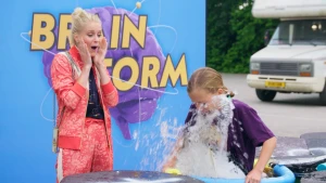 Foto van meisje dat in ton met water valt terwijl Janouk geschrokken toekijkt met handen op de wangen.