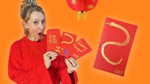 Foto van presentatrice Rosalie die rode enveloppen met gouden versiering laat zien.