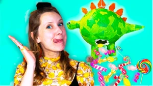 Foto van presentatrice Rosalie naast zelfgeknutselde pinata van groene dino waar snoepjes uit vallen.