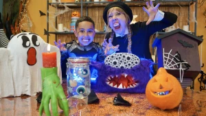 Foto van presentatrice Rosalie met kind in Halloweensetting met pompoenen, spook, ogen en monster op tafel.