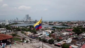Vlag van Colombia wappert in het midden. Daarachter beelden van stad en zee.