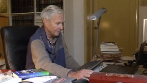 Foto van schrijver Jan Terlouw zittend aan een bureau.