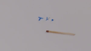 Een foto van drie verschillende oorbuisjes. Er ligt een lucifer naast om aan te geven dat ze kleiner zijn dan de kop van een lucifer. De ene is t-vormig, bij het middelste buisje zit er een extra stukje aan en het laatste buisje is een klein stukje buis.