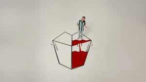 Een foto van presentator Bart. Hij staat in een ruimte met een witte vloer. Op de vloer is met tape een mensenhart getekend, bestaande uit vier vakken. Vanuit het vak rechtsboven stroomt een rode vloeistof naar het vak rechtsonder.