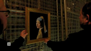 Een foto van het schilderij Meisje met de parel wordt opgehangen aan een rooster in een grot in Maastricht.