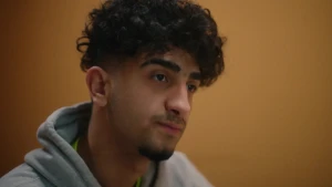 Jongen met donker haar en een hoodie aan.