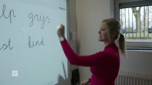 Een foto van een juf die op het digibord schrijft, je ziet de woorden grijs en kind.