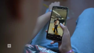 Een foto van iemand die een telefoon vasthoudt, op de telefoon zie je een filmpje met in beeld de tekst ADHD.