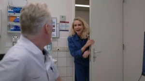 Janouk komt binnen bij dokter Hidde. Ze staat in de deuropening en dokter Hidde kijkt naar haar.