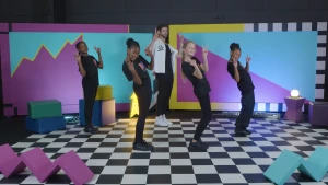 Foto van kinderen in zwarte kleren op geblokte ondergrond die dansmoves doen.