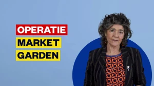 Foto van presentatrice Dieuwertje Blok voor een blauw scherm met de tekst operatie Market Garden.