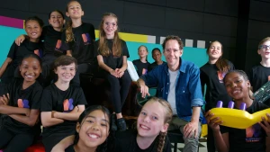 Foto van blije kinderen van het koor samen met zangcoach Michiel. 