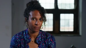 Presentatrice Astrid kijkt naar camera. Achter haar een raam.