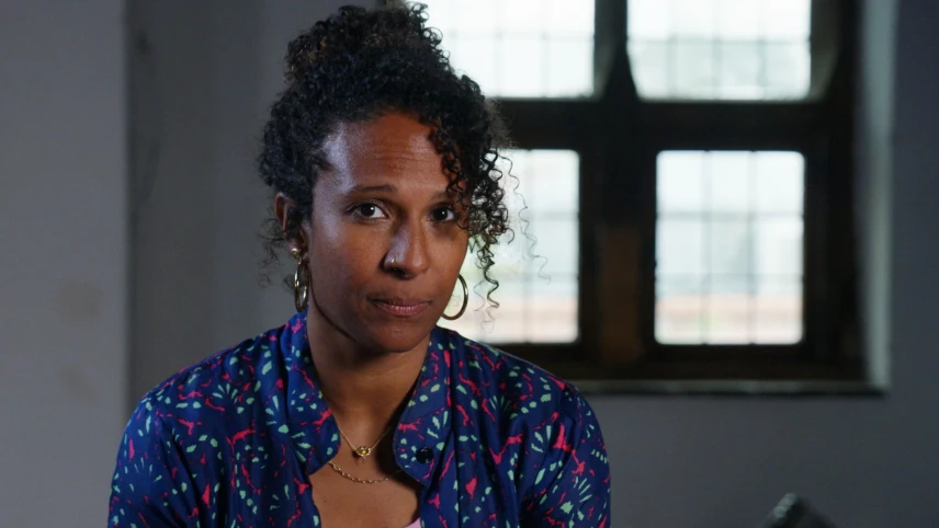 Presentatrice Astrid kijkt naar camera. Achter haar een raam.