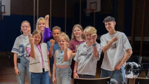 Thorn de Vries en Linde staan met Anne-Mar en kinderen. Ze hebben een gebalde vuist met stippen erop.