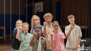 Meester Jesper en Chayenne staan met Anne-Mar met een groep kinderen. Ze hebben gebalde vuisten met stippen erop.
