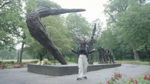Presentator Thirsa staat in een park bij het slavernijmonument.