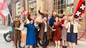 Foto van mensen die tijdens de bevrijding voor een Amsterdamse gevel staan.