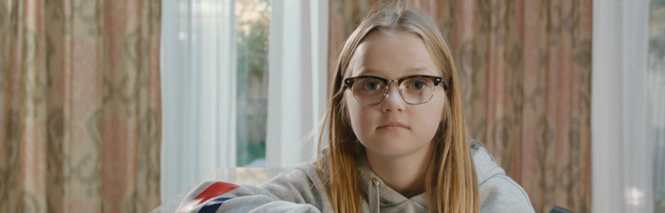 Een foto van Floor, ze zit op een kruk aan een bar in de keuken, met haar arm leunt ze op de bar.