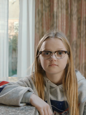 Een foto van Floor, ze zit op een kruk aan een bar in de keuken, met haar arm leunt ze op de bar.