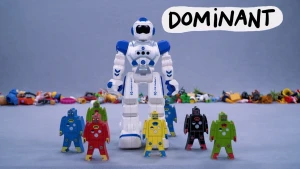 Beeld uit stopmotionanimatie met gekleurde robots op blauwe achtergrond. Achter ze staat een grote witte robot die boven de andere robots uittorent.