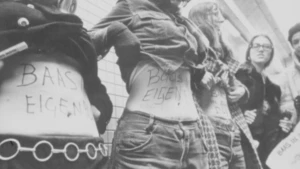 Zwart-wit foto uit de jaren zeventig van drie vrouwen met 'baas in eigen buik' op hun buik geschreven.