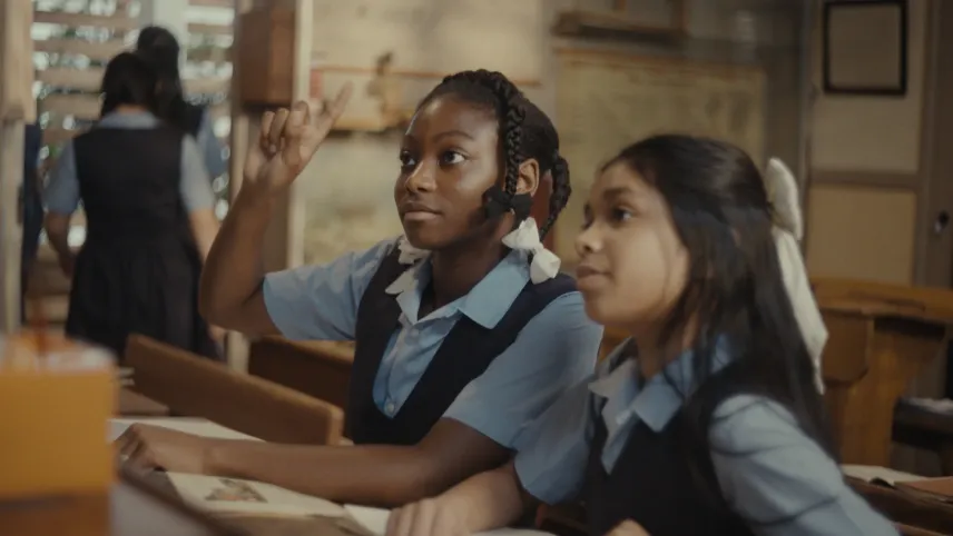 Een foto van twee meisjes in een schoollokaal in schooluniformen.