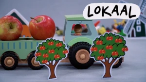 Beeld uit stopmotionanimatie waarin een speelgoedtractor met twee appels door een Hollands landschap rijdt met appelbomen en een molen op de achtergrond.