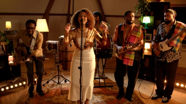 Foto van muzikanten en zangeres die op een gezellige zolder een liedje zingen over Suriname.